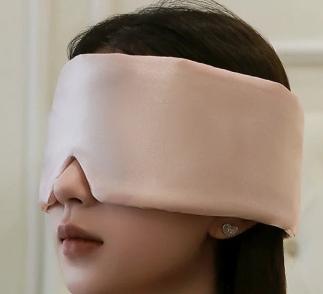 Soft blush silk sleep mask worn by an adult
